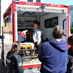 EMT workers showing a young boy the back of an ambulance