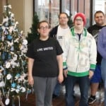 a people standing next to a Christmas tree