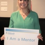 a woman holding a 'I am a Mentor' sign