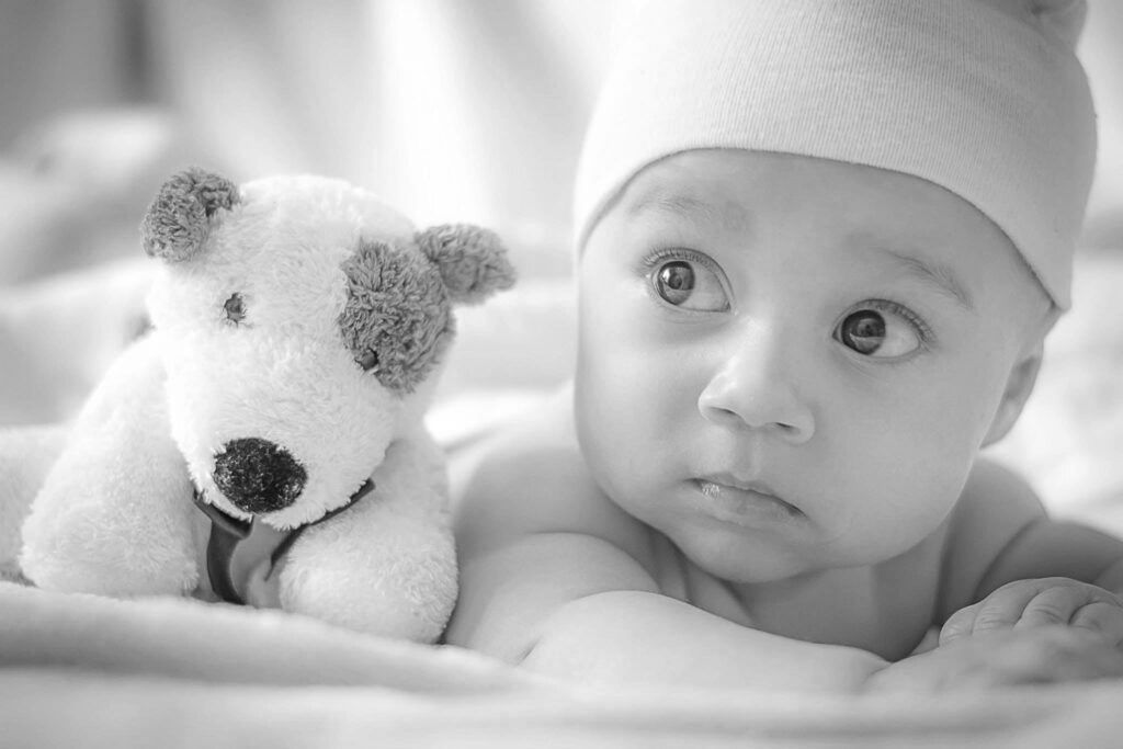 Baby laying beside stuffed animal